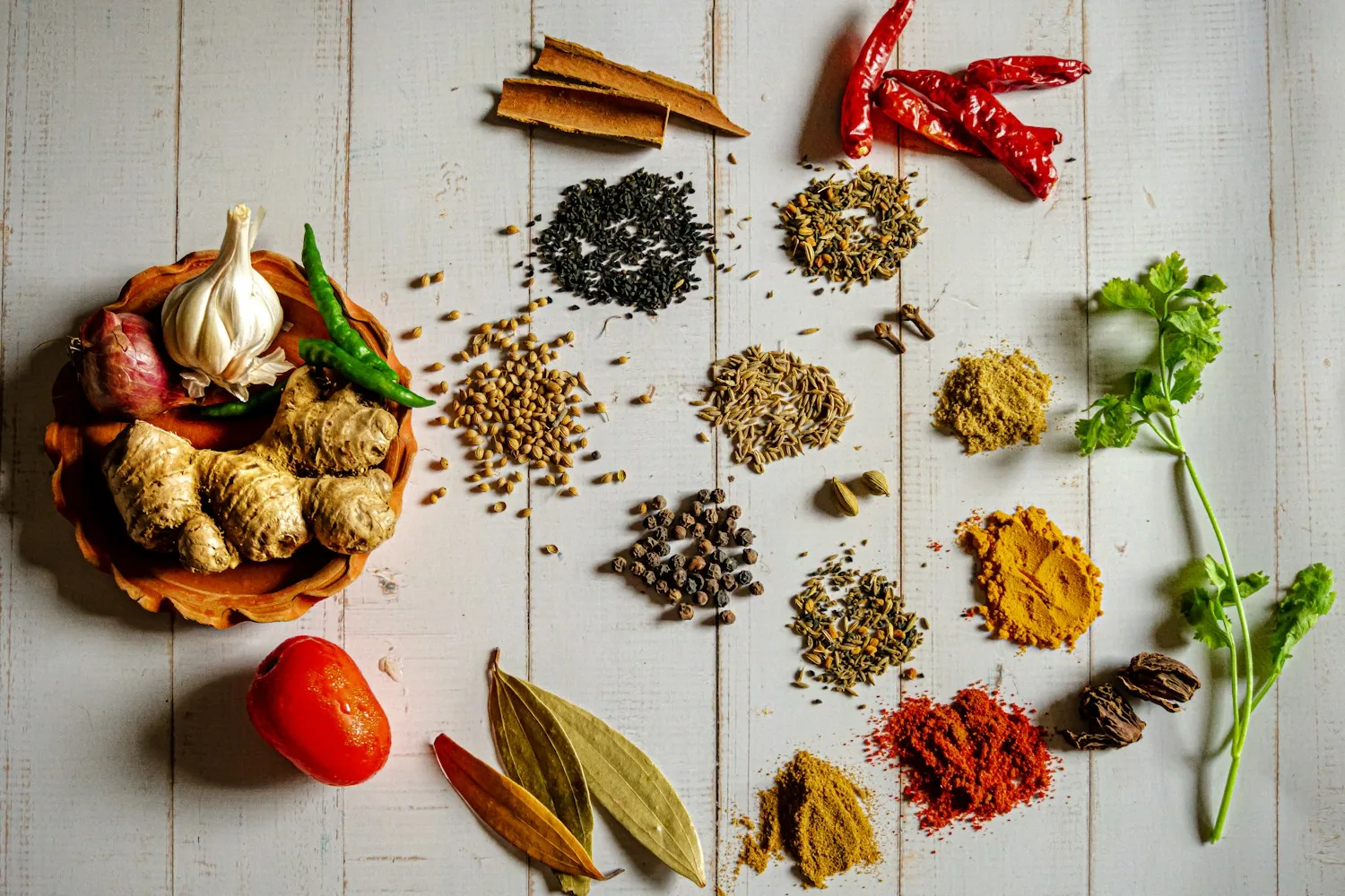 Whole Indian spices, garlic, ginger and red chillies arranged on a wooden table