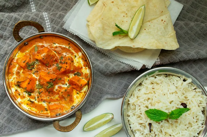 Curry in a kadai served with rice and papad